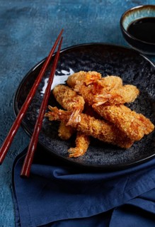 Shrimp in tempura, deep fried, on a black plate, with soy sauce, close-up, top view, no people
