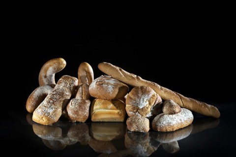 Assortment of different loaves of bread on black background