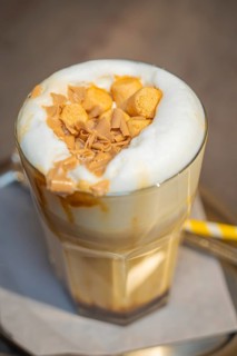 A latte with a creamy topping and biscuits served on a table, autumn creations, Cafe Kuh,