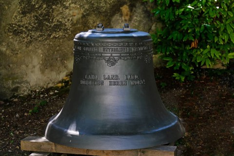 Church bell in the garden of St John's Church, inscription Land, Land, Land hear the Lord's word,