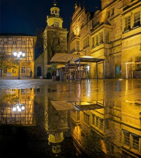 Town hall and church Marketplace illuminated Reflection in puddle Panorama Rinteln Germany