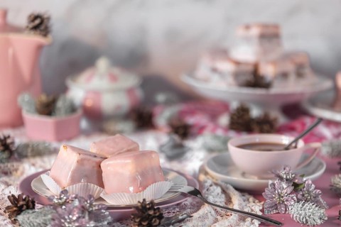 Pink glazed cakes, punch doughnuts and coffee on a table decorated in pink and white for Christmas