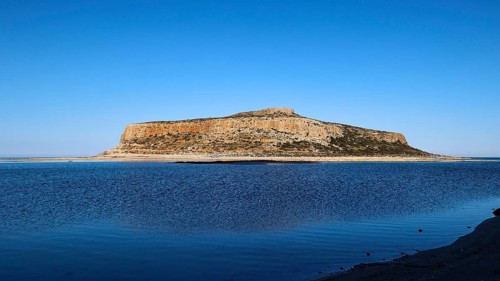Rocky island in front of calm blue sea under clear sky, peaceful scene, Gramvoussa, Gramvoussa