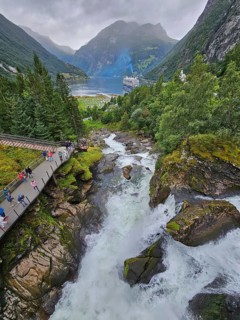 An impressive landscape with a raging waterfall, surrounded by green mountains and forests, with a