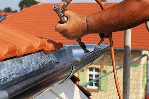 Roofer doing tinsmith work on a gutter