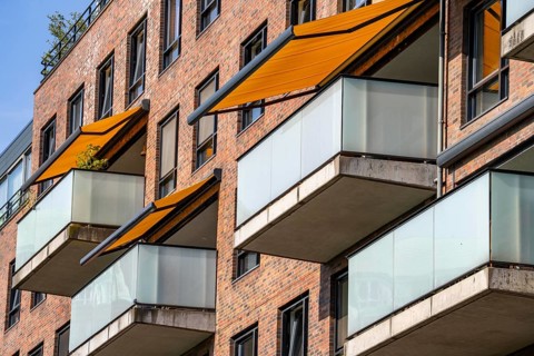 Residential building, flat with balconies and orange sun protection blinds, balcony awning