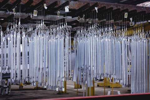 Finished galvanised steel parts lie in the factory hall of a surface finishing factory of the