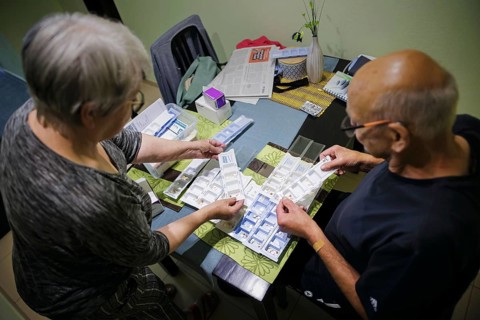 Symbolic photo on the subject of taking medication in old age. Two senior citizens sort various