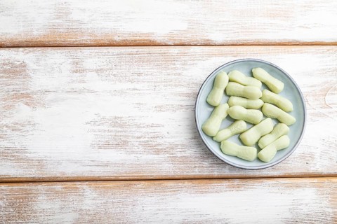 Jelly celery candies on white wooden background. copy space, top view, flat lay