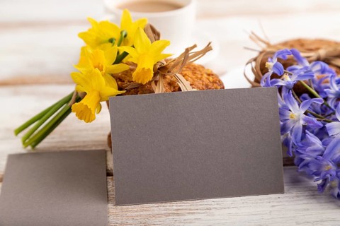 Gray paper business card mockup with oatmeal cookies with spring snowdrop flowers bluebells,