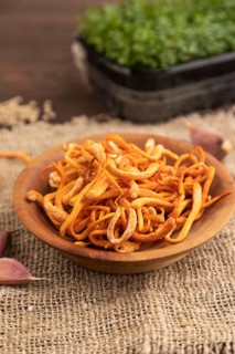 Fresh Cordyceps militaris mushrooms on brown wooden background with microgreen, herbs and spices.