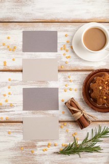 Gray paper business card mockup with cup of coffee and cake on white wooden background. Blank, top