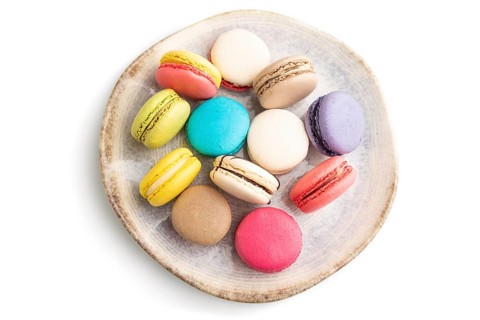Multicolored macaroons on ceramic plate isolated on white background. top view, still life, flat
