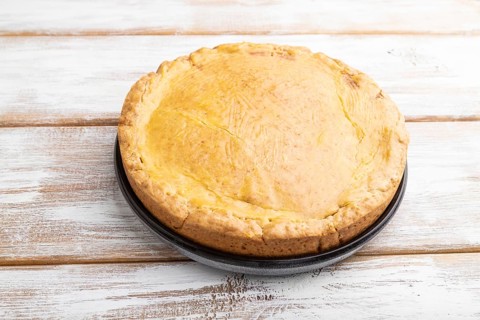 Autumn onion pie and cup of coffee on white wooden background. Side view, close up