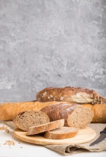 Sliced bread with different kinds of fresh baked bread on a gray concrete background. side view,