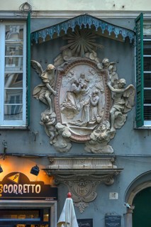 Relief group of saints and angel sculptures under a canopy on a residential building in the