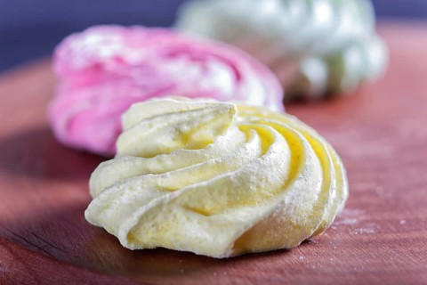 Colored meringues on wooden board, selective focus, close up