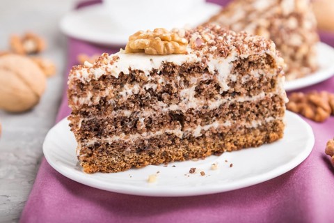 Homemade cake with milk cream and walnuts with cup of coffee on a gray concrete background and