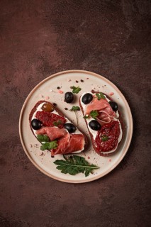 Sandwiches with cheese and prosciutto, dried tomatoes and olives, breakfast on a plate