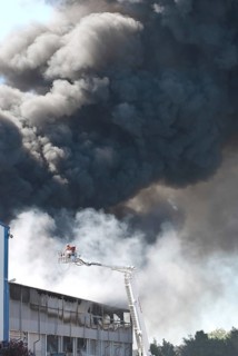Two firefighters with protective clothing and gas masks in aerial work platform, lifting platform