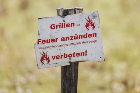 A sign with the inscription 'Barbecues and lighting fires prohibited' stands in a meadow in Berlin,