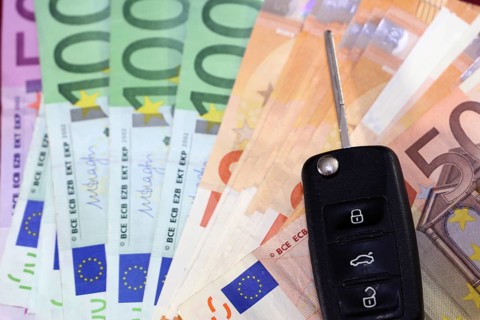Euro banknotes and car keys as a symbol for car costs