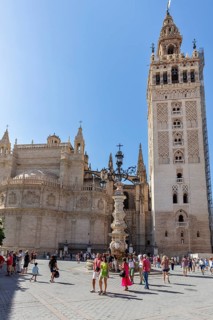 Gothic cathedral with high tower and lively square on a sunny day, Seville