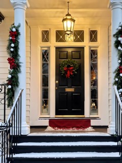 Festive front porch with holiday garlands wrapped around the columns, a wreath hanging on the door,
