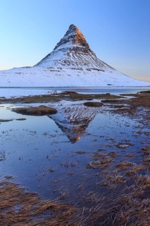 Pointed mountain reflected in fjord at low tide, snow, winter, morning light, Kirkjufell,
