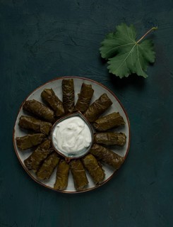 Dolma, cabbage rolls in grape leaves, Traditional Armenian dish, with white sauce, top view,