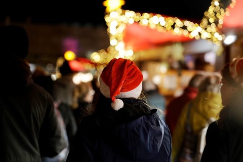 Person with a red cap at an illuminated Christmas market at night, Cologne, North Rhine-Westphalia,