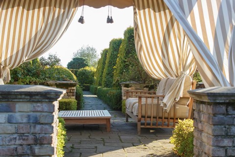 Modern gazebo in cottage garden with natural stone path and topiary. Modern landscape design