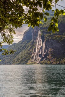 The majestic Seven Sisters waterfall flows down a forested mountain into the tranquil Gairanger