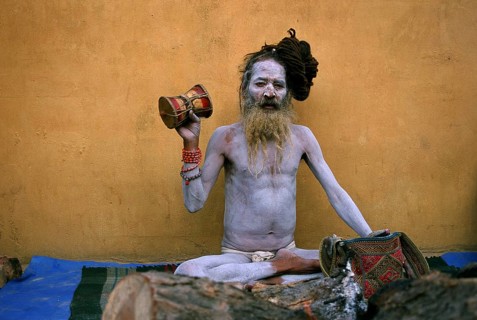 Hindu ascetic, sadhu from the naga sect, Nepal. His body is covered with ashes, he is playing