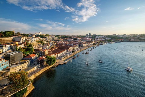 View of Vila Nova de Gaia city and Douro river with tourist boats on sunset. Porto, Portugal,