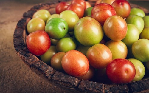 Cherry plum tkemali, fruit, plum variety, in a wooden plate, Georgian cuisine, top view, no people