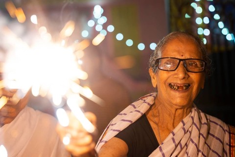 An elderly woman of Pramod Talukdar Memorial Old Age Home burn sparkler crackersas she celebrate