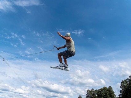 Young man jumping and flying with wakeboard, water sports and water skiing in the wakepark
