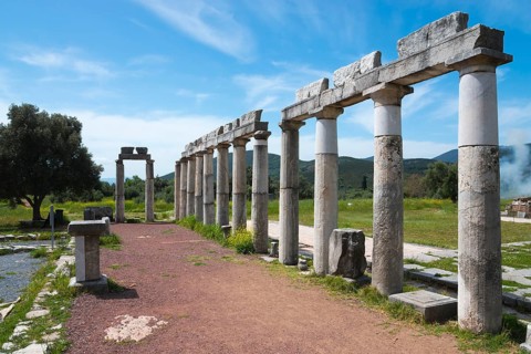 Ruins of ancient tall columns stretching along a path under a clear blue sky, Messene, ancient