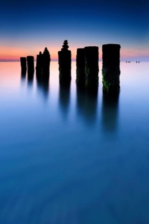Stone pyramids on old groynes with algae in the water on the beach of the Baltic Sea, long exposure
