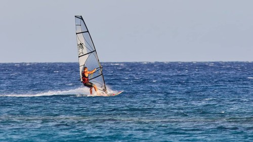 A windsurfer with a stylish sail glides over the sea surface, windsurfer, Meltemi windsurfing spot,