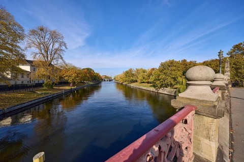 Luther bridge over the river Spree with Bellevue bank, autumnal trees and blue sky with