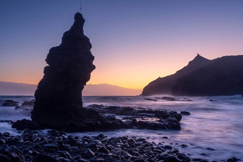 Sunrise on the beach at Playa de La Caleta with Punta San Lorenzo. Rocks and sea. Blue sky.