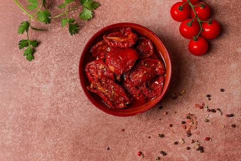 Dried tomatoes, in a bowl, top view, on a brown background