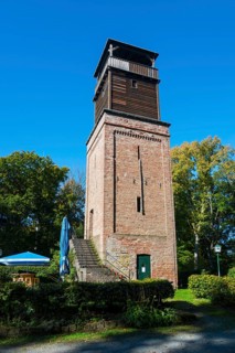 Old brick watchtower surrounded by trees under a clear sky, observation tower Hildesheimer Wald,