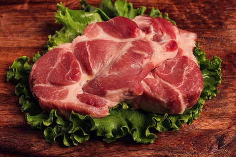 Raw pork steak, two pieces, on a wooden background