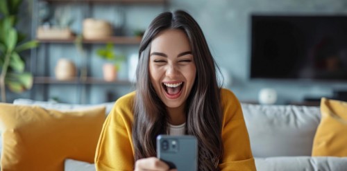 Younge Caucasian happy girl playing on smartphone apps, betting money online and shopping online,