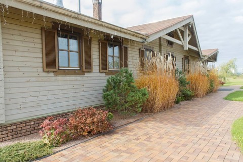 Modern restaurant with green lawn, tile path and landscape design with ornamental grasses and