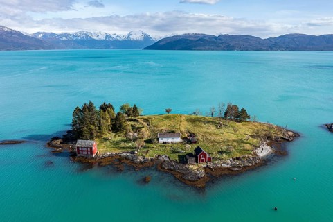 Aerial view of typical red houses on an island in the Hardangerfjord, mountain range in the back,