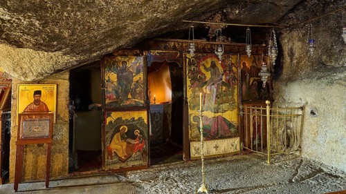 Orthodox church in a stone cave with iconostasis, sacred images and candles that create a spiritual